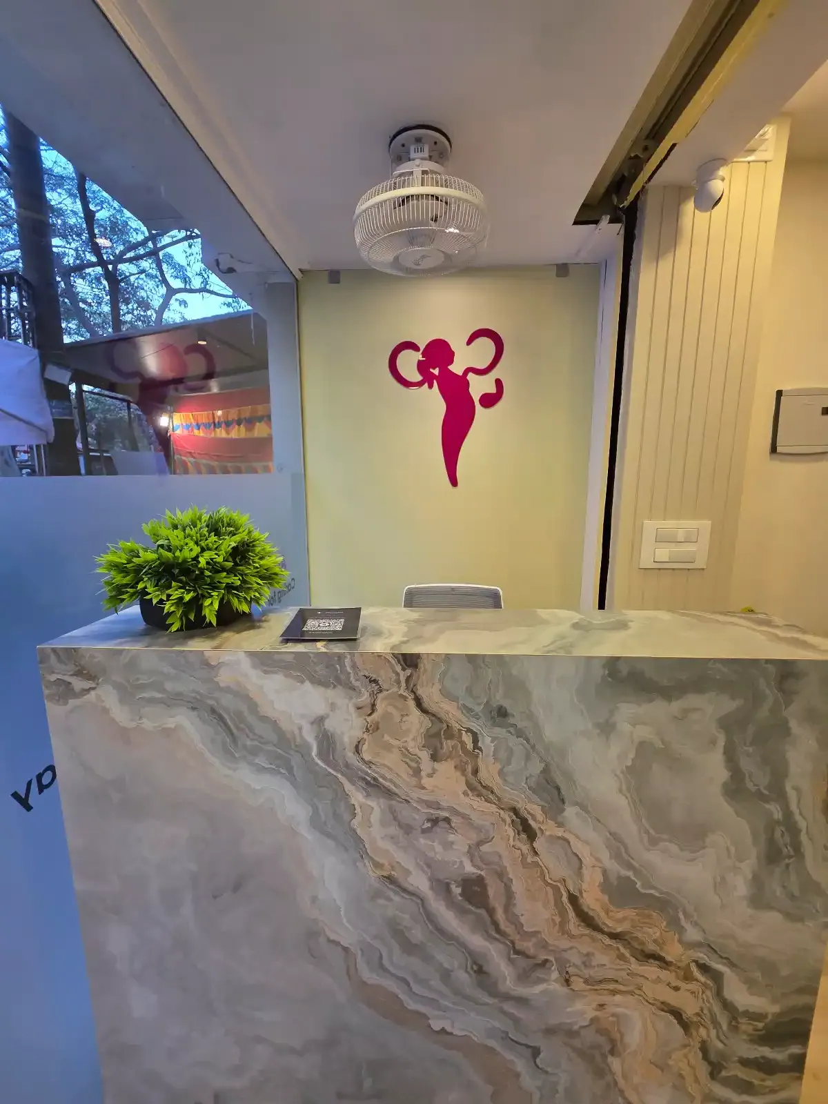 Reception desk at Aarogya Women’s Clinic with marble counter and the clinic’s magenta logo