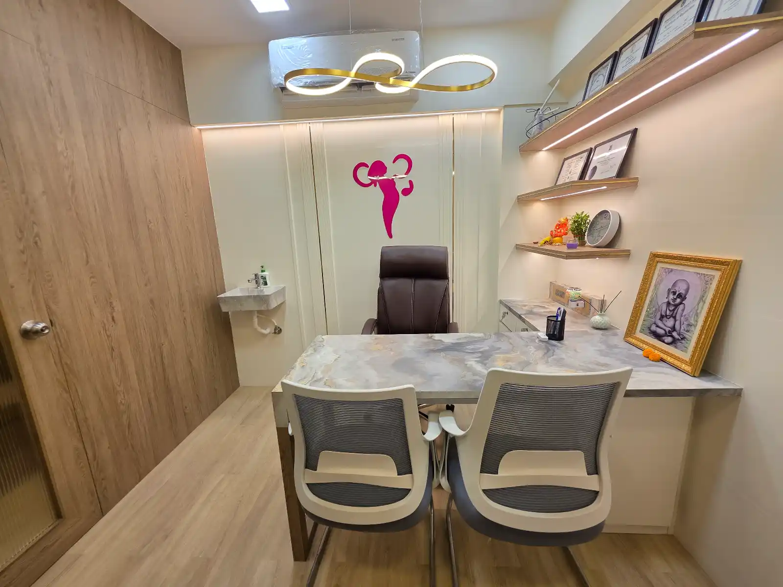 Consultation room at Aarogya Women’s Clinic with marble desk, patient chairs, and Dr. Pallavi’s framed medical certificates on display