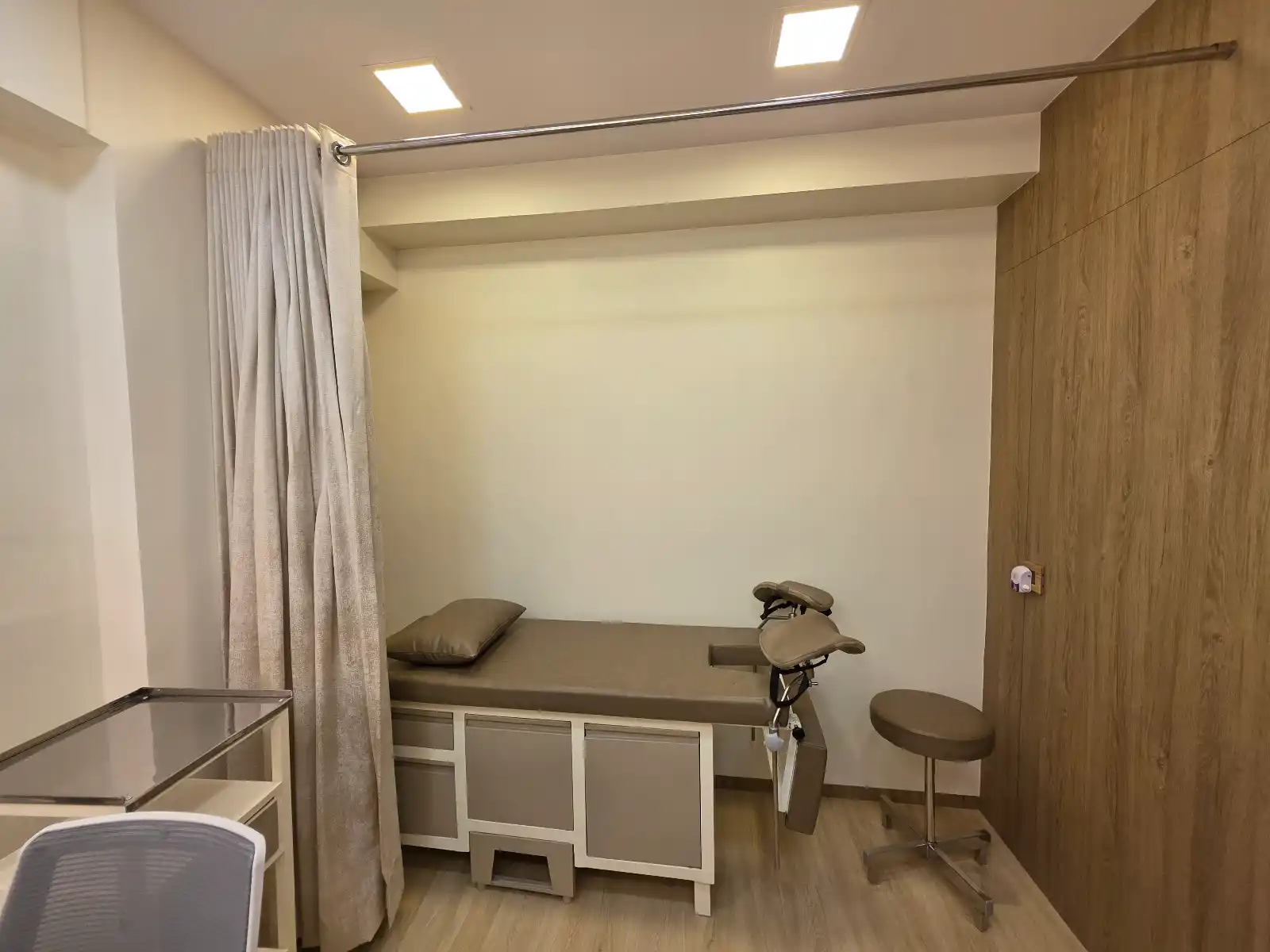 Examination room at Aarogya Women’s Clinic with consulting bed, exam stool, and privacy curtain